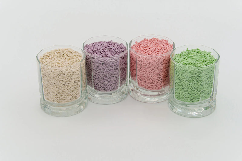 4 cups filled with various cat litter scents. From left to right, Milk, Lavender, Peach, Green Tea